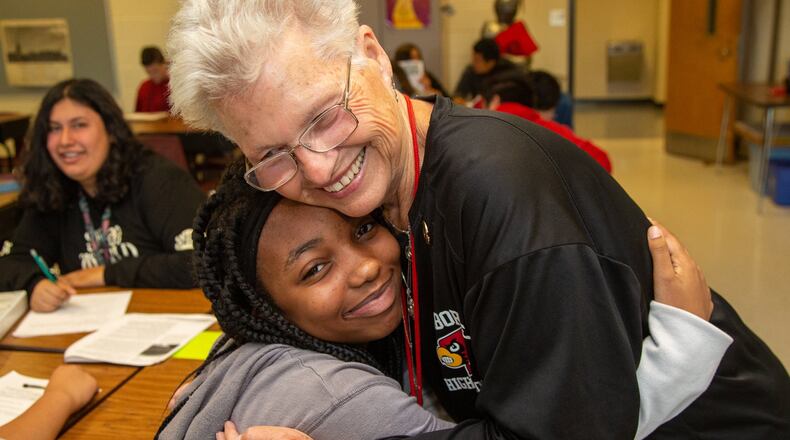 Osborne High School teacher Annette Hansard gets a hug from Ciara Witte during class on Friday, Sept. 20, 2019. She recently celebrated her 50th year of teaching social studies in that Cobb County school. She said she’s taught about 15,000 students over the last half century. PHIL SKINNER