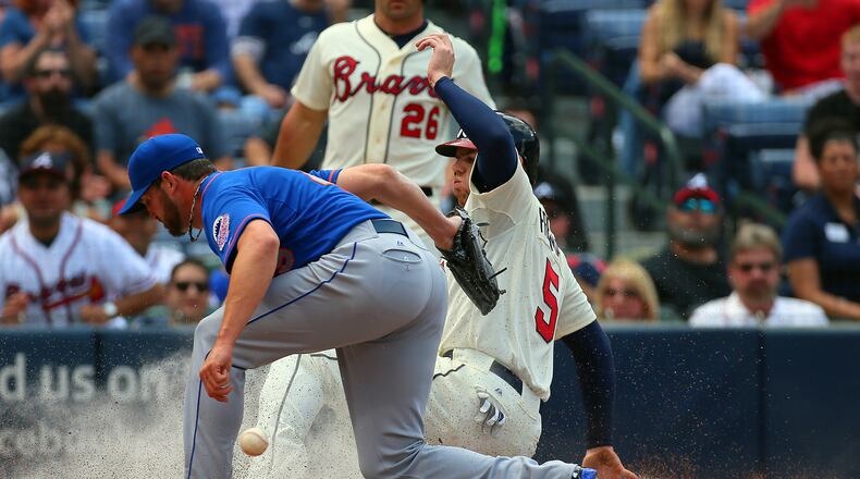 The Braves' Freddie Freeman scores from third base on a wild pitch by Mets' pitcher Jonathon Niese, who covers the plate but can't hold on to the ball. The score gave the Braves a 4-0 lead in the third inning.