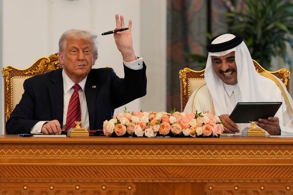 President Donald Trump holds up a pen given by Qatar's Emir Sheikh Tamim bin Hamad Al Thani as they exchange documents during a signing ceremony at the Amiri Diwan in Doha, Qatar, Wednesday, May 14, 2025. (AP Photo/Alex Brandon)
