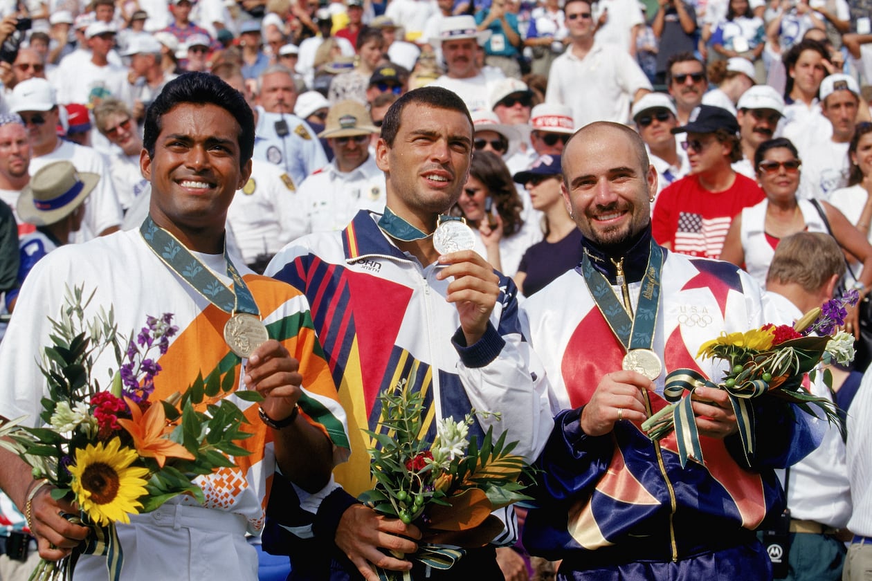 American tennis star Andre Agassi celebrates after receiving his gold medal at the 1996 Olympics in Atlanta. Leander Paes of India (left) earned the bronze and Sergi Bruguera of Spain (center) took the silver medal. (Photo by Gary M. Prior/Getty Images)