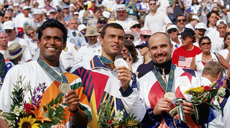 American tennis star Andre Agassi celebrates after receiving his gold medal at the 1996 Olympics in Atlanta. Leander Paes of India (left) earned the bronze and Sergi Bruguera of Spain (center) took the silver medal. (Photo by Gary M. Prior/Getty Images)