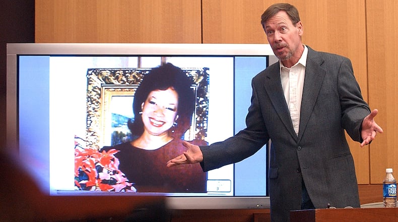Phillip Anthony "Tony" Harwood, standing, accused shooter in the January 1987 death of socialite Lita Sullivan, pictured on the screen, shows the jury how James Sullivan asked him to kill his wife, during James Sullivan's murder trial in a Fulton County courtroom on March 6, 2006. (AJC file)
