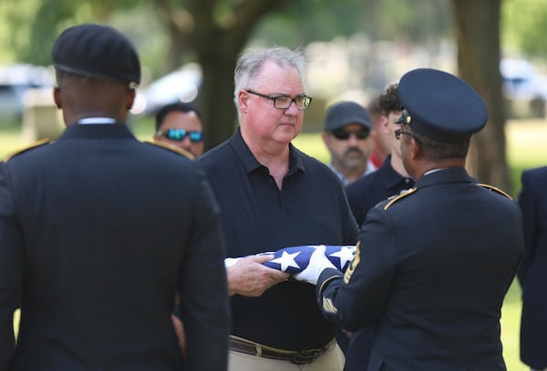 Staff Sgt. Kobe Green and Master Sgt. Derrick Bailey, right, present Mark Bailey with an American flag during during a military funeral for his aunt, 75-year-old Pfc. Reba C. Bailey, a former missing person cold case named Seven Doe, Tuesday, July 1, 2025 at Mount Olivet Catholic Cemetery in Chicago. (AP Photo/Talia Sprague)