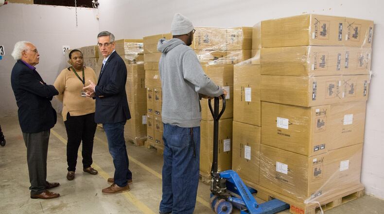 (left to right) Chairman of the Elections Board Samuel Tillman, Director of Voter Registration and Elections Erica Hamilton and Secretary of State Brad Raffensperger talks as Kentavious Ford unloads a pallet from a shipment of Georgia’s new secure paper-ballot voting machines at the Dekalb County Voter Registration and Elections offices in Avondale Estates on Monday December 30, 2019. (Photo by Phil Skinner).