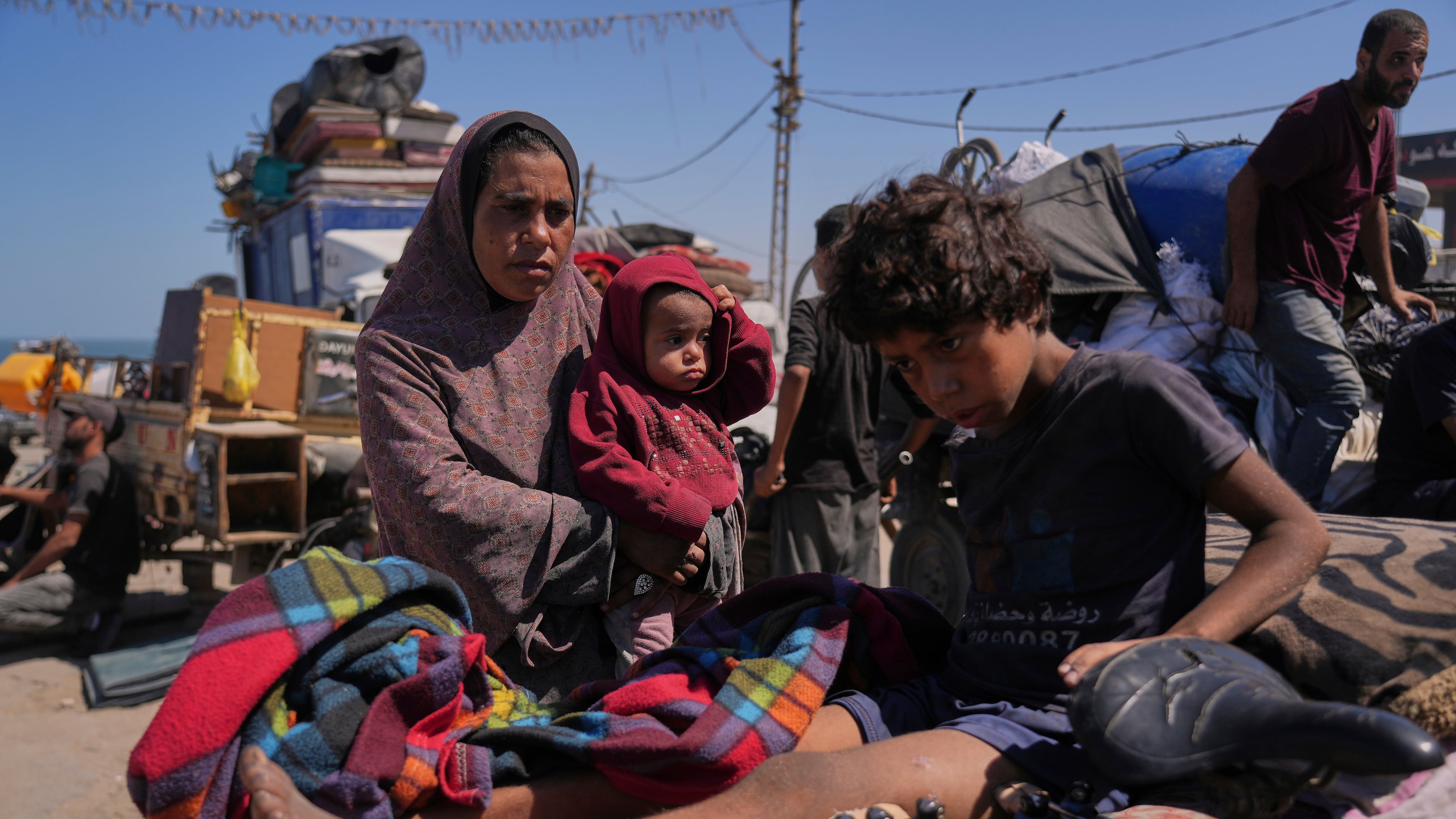 Amal Al-Qishawi, follows her injured son, Yasser, 11, carried on a bicycle by his father Rafiq Al-Qishawi, as they flee northern Gaza Strip walking along the coastal road, near Wadi Gaza, Saturday, Sept. 20, 2025. (AP Photo/Abdel Kareem Hana)