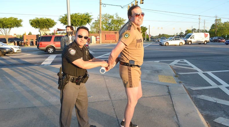 Atlanta radio host “Southside” Steve Rickman poses for a photo with the Johns Creek police officer who pulled him over for running a red light, Phil Nguyen.