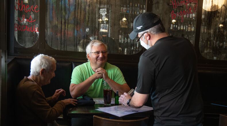 Shane Goode (right), a 1920 Tavern employee, delivers drinks to Bart Van Linden and his mother, Sabine Van Linden, at the Roswell restaurant.  Courtesy of Steve Schaefer