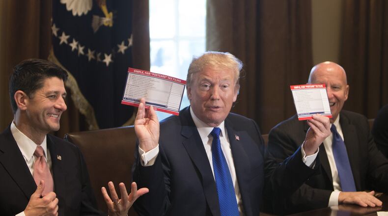 President Donald Trump on Thursday displays examples of what a “postcard” tax return might look like under the Republican tax plan. He’s flanked by U.S. House Ways and Means Committee Chairman Kevin Brady, R-Texas, right, and House Speaker Paul Ryan, R-Wis., inside the Cabinet Room at the White House. Republican lawmakers unveiled a sweeping rewrite of the tax code Thursday, outlining a $1.51 trillion plan that would cut corporate taxes to 20 percent while delivering more modest savings for middle-class families. (Tom Brenner/The New York Times)