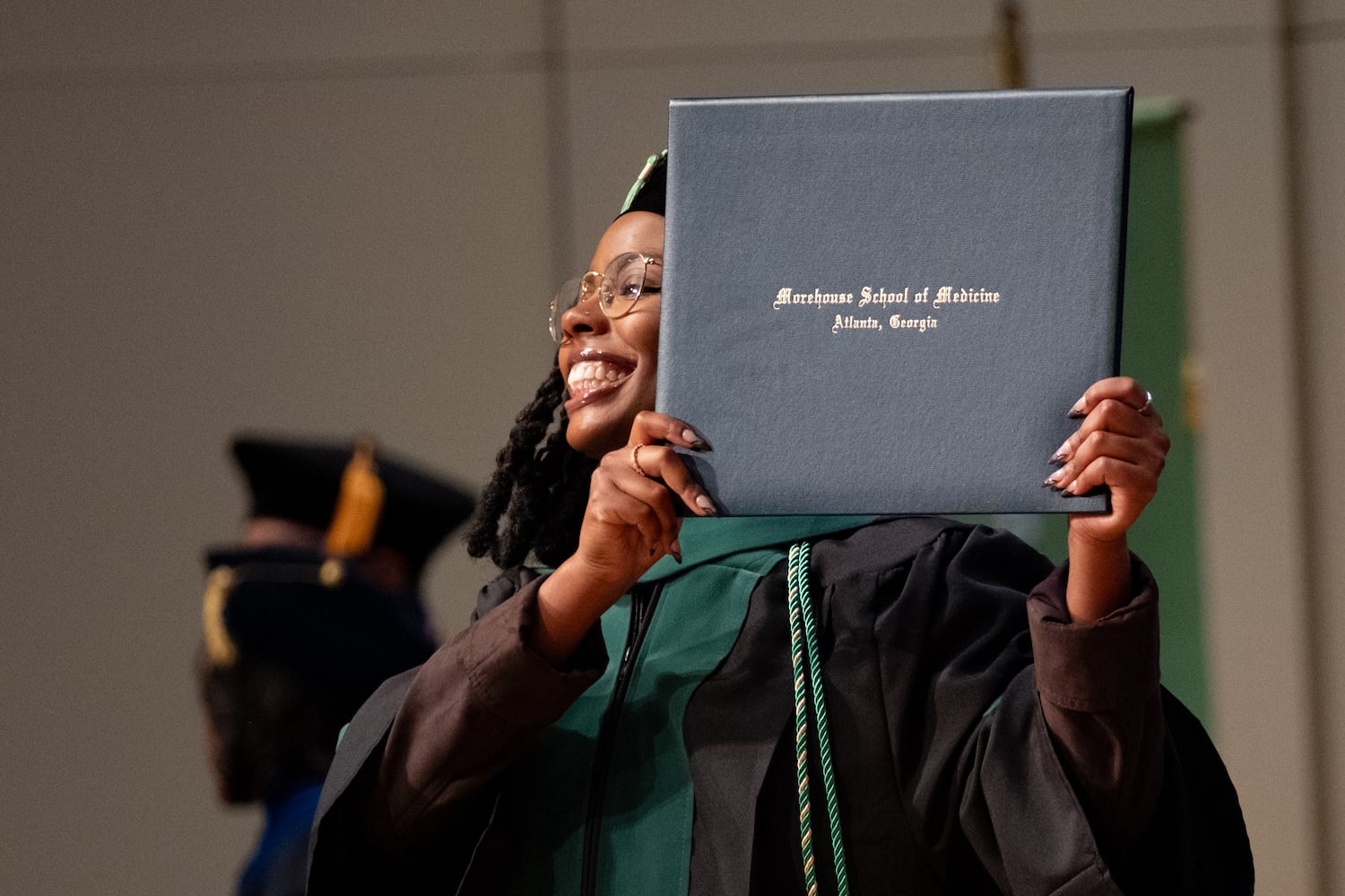 Dr. Mikaela Jarrell holds up her diploma during the Morehouse School of Medicine graduation ceremony on Saturday, May 16, 2026, in Atlanta. (Ben Gray for the AJC)