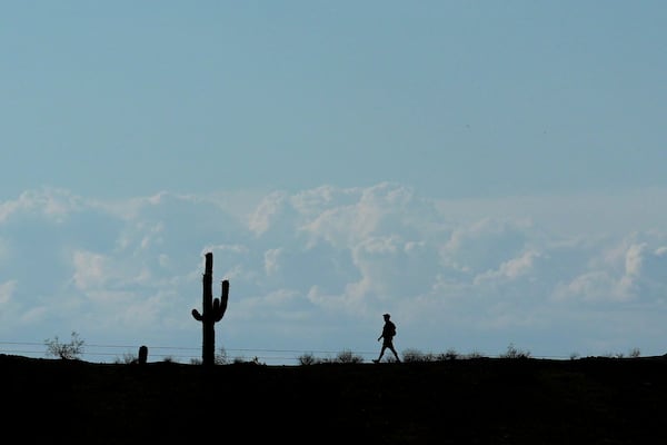 Storm clouds form in the distance as a hiker walks along a path in South Mountain Park Wednesday, June 4, 2025, in Phoenix. (AP Photo/Ross D. Franklin)