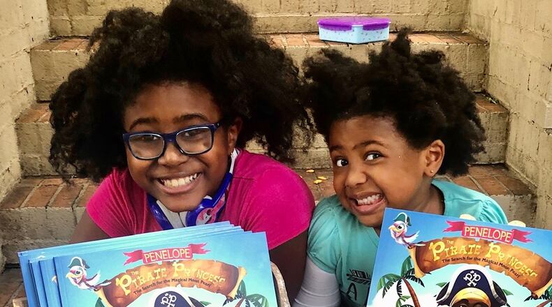 Selah Thompson, founder of The Empowered Readers Literacy Project with her little sister, Syrai, shown with the first book of Selah's "Penelope the Pirate Princess" series.