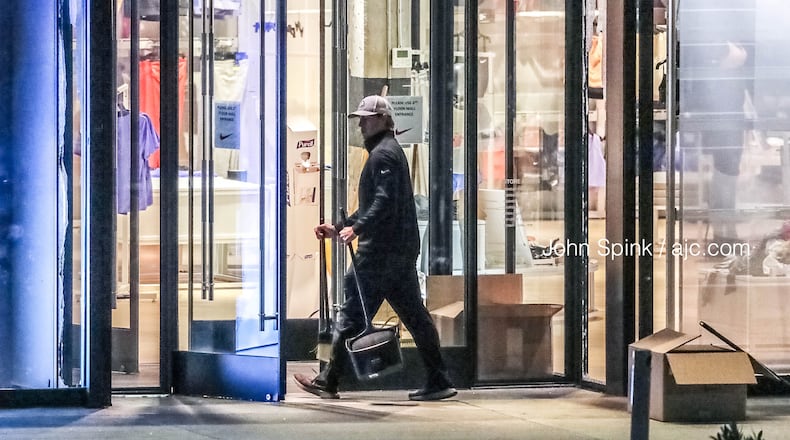 A worker cleans up broken glass at the Nike store at Lenox Square after a burglary Monday morning.
