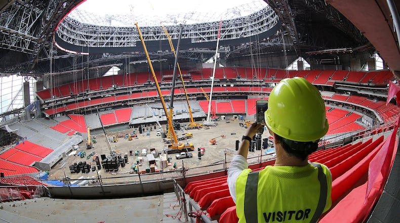 On a Thursday tour of Mercedes-Benz Stadium, a visitor snaps a photo showing many seats installed and the installation of panels for the halo-shaped video board underway. (Curtis Compton/ccompton@ajc.com)