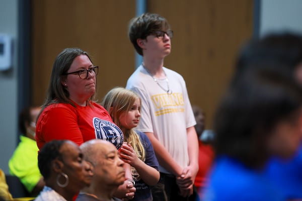 Jennifer Alexander-Sanchez, left, stands next to her two children, Willow Alexander, 10, center, and Grayson Alexander, 14, as they stand in support of a speaker during the public comment portion of the DeKalb County School Board meeting on April 20, 2026 in Stone Mountain. Willow is a student at Evansdale Elementary, which is one of the schools proposed for closure. (Jason Getz/AJC)