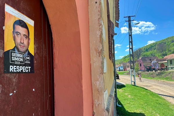 A presidential campaign poster is placed on a door in the village of Floresti, in Romania's central Transylvania region, Thursday, April 24, 2025. (AP Photo/Stephen McGrath)