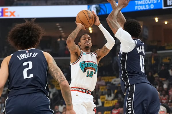 Memphis Grizzlies guard Ja Morant (12) shoots the ball past Dallas Mavericks center Dereck Lively II (2) and forward Naji Marshall, right, during the first half of an NBA play-in tournament basketball game Friday, April 18, 2025, in Memphis, Tenn. (AP Photo/George Walker IV)
