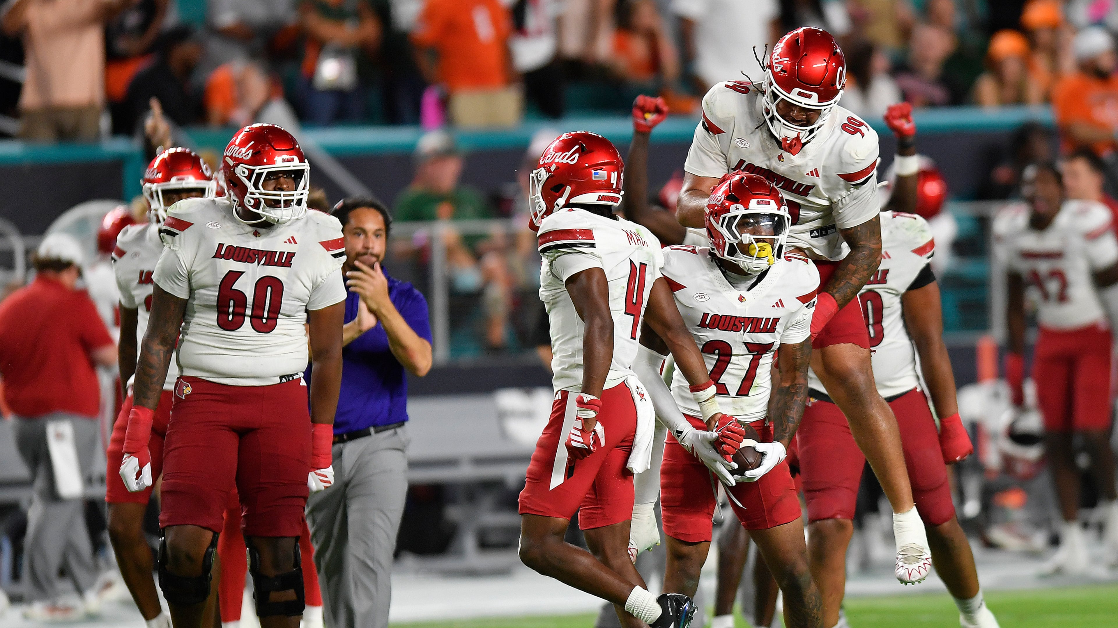 Louisville defensive back Jojo Evans Jr. (27) celebrates after intercepting a pass with defensive lineman Jordan Guerad (99) during the second half of an NCAA college football game against Miami, Friday, Oct. 17, 2025, in Miami Gardens, Fla. (AP Photo/Michael Laughlin)