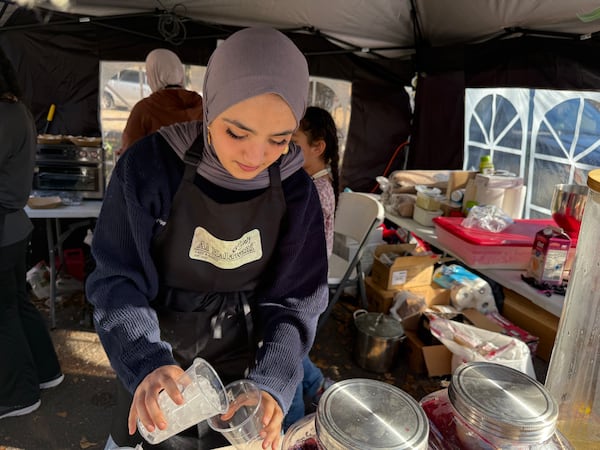Luma Younis, a medical school student, pours tea at the desserts stall her family set up at the festival. (Ariel Hart/AJC)