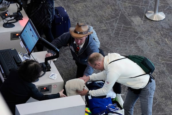 A traveler takes an item out of his suitcase while attempting to check-in his luggage at San Francisco International Airport ahead of the Memorial Day holiday weekend in San Francisco, Thursday, May 22, 2025. (AP Photo/Godofredo A. Vásquez)