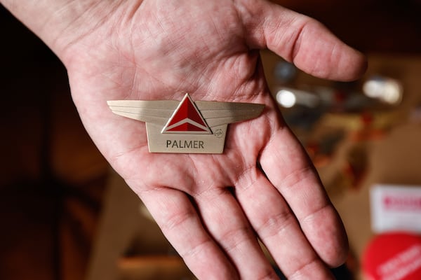 Mathew Palmer, a former Delta Air Lines employee, holds his name tag at his home in Atlanta on Thursday, Oct. 9, 2025. He was a flight attendant for the company for nearly 18 years before being dismissed because of a social media post about the death of conservative activist Charlie Kirk. (Natrice Miller/AJC) 