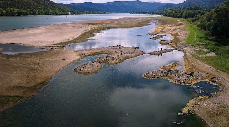 People walk on sandbanks exposed by record-low water levels in the Danube River after drought and extreme heat near Nagymaros, Hungary, on Aug. 18, 2026. (AP Photo/Bela Szandelszky)