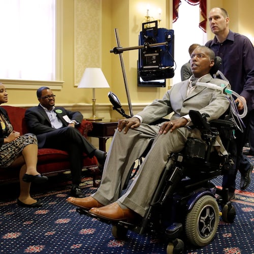 FILE - Former Baltimore Ravens NFL football player O.J. Brigance, center, current senior advisor to player development, is pushed by a nurse outside of a committee room in Annapolis, Md., March 10, 2015, after testifying to Maryland lawmakers against a right-to-die bill. (AP Photo/Patrick Semansky, File)
