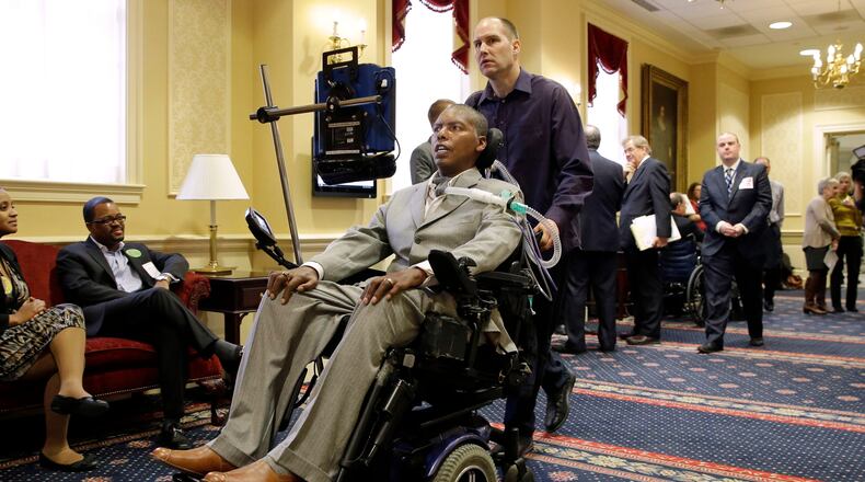FILE - Former Baltimore Ravens NFL football player O.J. Brigance, center, current senior advisor to player development, is pushed by a nurse outside of a committee room in Annapolis, Md., March 10, 2015, after testifying to Maryland lawmakers against a right-to-die bill. (AP Photo/Patrick Semansky, File)