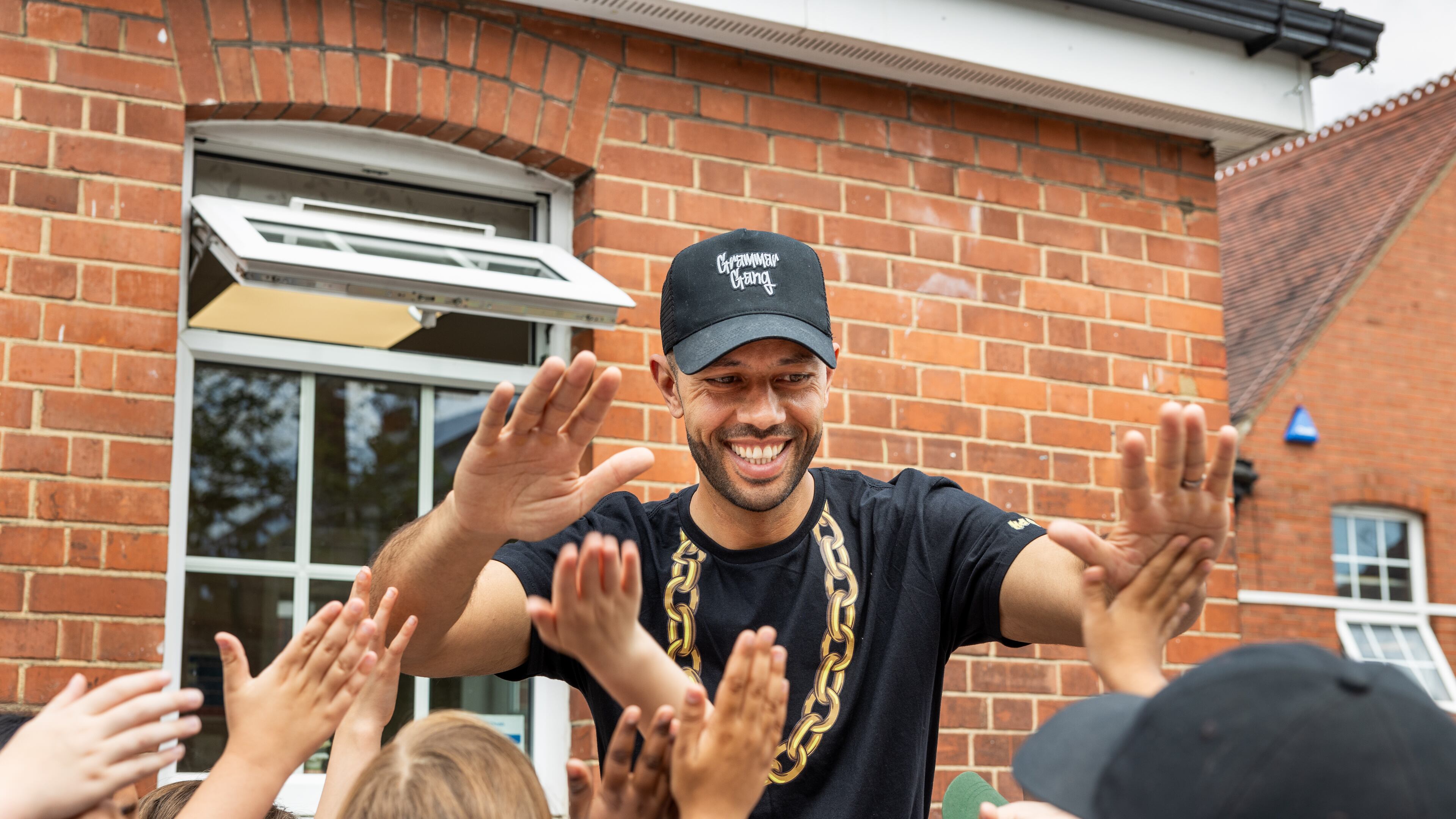 Jacob Mitchell with young fans at Foulds School, his alma mater, in High Barnet, England, on June 24, 2024. Under the name of his alter ego, MC Grammar, Mitchell has become a wildly popular performer whose rhymes have made reading and grammar all the rage among young people across Britain. (Jeremie Souteyrat/The New York Times)