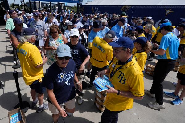 Tampa Bay Rays fans pick up schedule magnets ars they enter Steinbrenner Field before a baseball game between the Rays and the Colorado Rockies Friday, March 28, 2025, in Tampa, Fla. (AP Photo/Chris O'Meara)