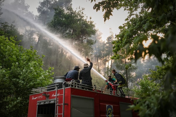 An emergency responder with the Syrian Civil Defense, known as the White Helmets, works to extinguish a wildfire near the town of Rabia, in Syria's Latakia countryside, Sunday, July 6, 2025. (AP Photo/Ghaith Alsayed)