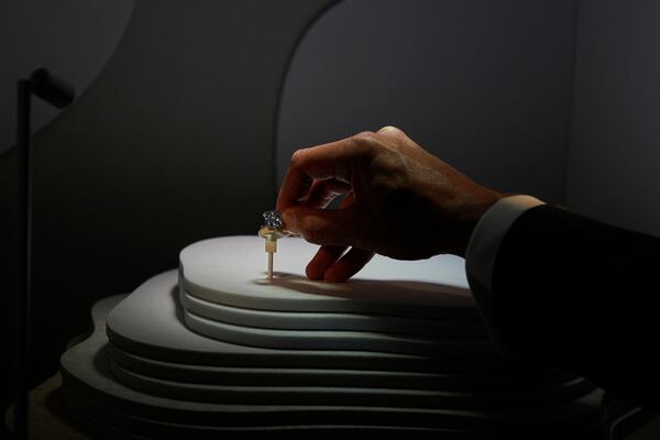 An employee of Sotheby's Dubai holds The Mediterranean Blue diamond during its worldwide debut in Abu Dhabi, United Arab Emirates, Tuesday, April 8, 2025. (AP Photo/Altaf Qadri)
