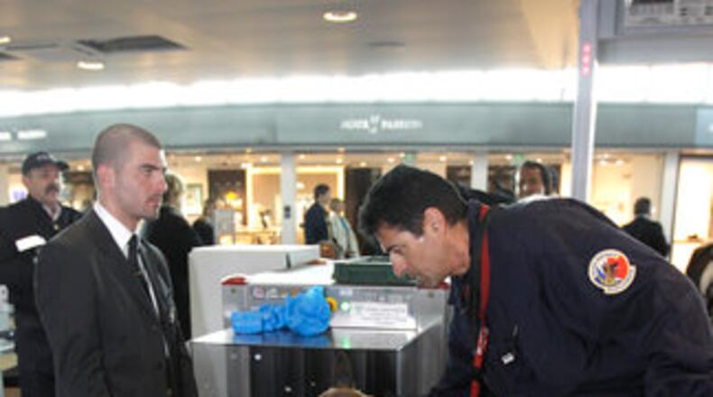 A police officer with a sniffer dog checks a passenger's suitcase at a security control before boarding their plane, at the Nice-Cote d'Azur airport, in Nice, France, Wednesday, May 4, 2011. Security personnel remain vigilant following the death of al-Qaida's Osama bin Laden. (AP Photo/Lionel Cironneau)
