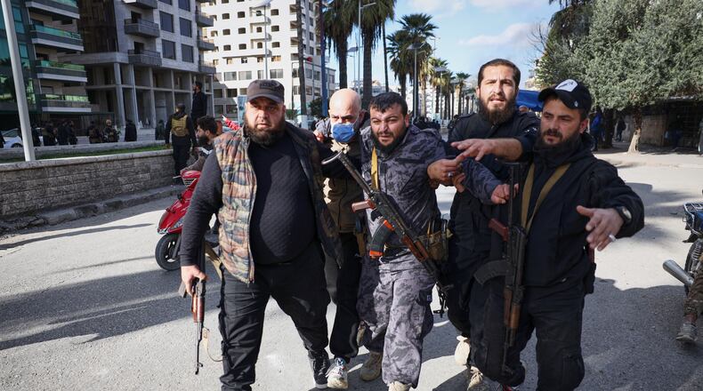 A police officer injured by a thrown stone is helped away from the area after clashes erupted between Alawite protesters from the Alawite religious minority and counterprotesters, two days after a bomb in an Alawite mosque in Homs killed eight people and wounded 18 during Friday prayers, in Latakia, Syria's coastal region, Sunday, Dec. 28, 2025. (AP Photo/Omar Albam)