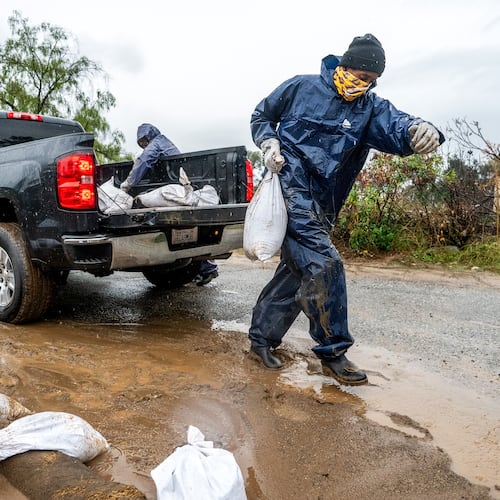 James Jones places a sandbag to prevent water from running off a property scorched in the Eaton Fire in Altadena, Calif., as the region remains under flash flood warnings on Saturday, Nov. 15, 2025. (AP Photo/Noah Berger)