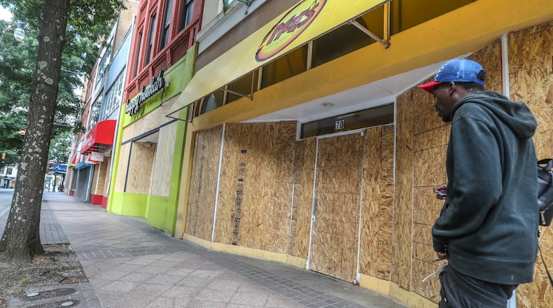 June 1, 2020 Atlanta: Businesses along Peachtree Street across from Woodruff Park were all boarded up Monday morning after losing glass to vandals. Atlantans coming into downtown for work on Monday, June 1, 2020 saw boarded up buildings and debris strewed across sidewalks and streets following weekend cleanup efforts. Over the weekend vandals left a trail of smashed windows and graffiti in their wake. A third day of protests in Atlanta over recent incidents of police violence across the country ended with 64 arrests. According to Atlanta police, the arrests were made without major incidents. A citywide curfew went into effect at 9 p.m. Sunday. JOHN SPINK/JSPINK@AJC.COM