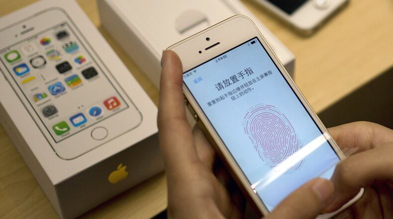 The Sept. 20, 2013 file photo shows a customer configuring the fingerprint scanner technology built into iPhone 5S at an Apple store in Wangfujing shopping district in Beijing.