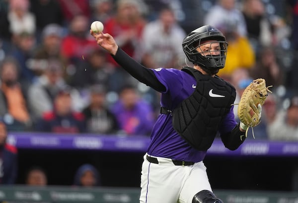 Colorado Rockies catcher Jacob Stallings throws to first base after fielding an infield single hit by Atlanta Braves' Eli White in the fourth inning of a baseball game Monday, April 28, 2025, in Denver. (AP Photo/David Zalubowski)