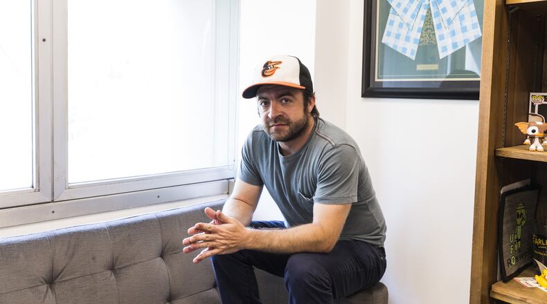 Derek Waters, the co-creator of Comedy Central’s “Drunk History,” in Los Angeles, Aug. 4, 2016. Waters loves going back to Baltimore to see family and friends; the Orioles cap can always be found in his carry-on. “I’m not a jock, I just love my town,” he said. (Emily Berl/The New York Times)