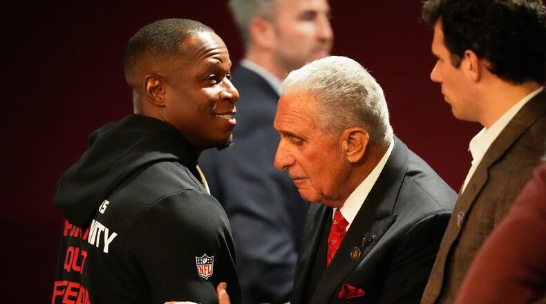 Atlanta Falcons owner Arthur Blank (right) hugs head coach Raheem Morris after the game against the New Orleans Saints on Sunday. (Mike Stewart/AP)