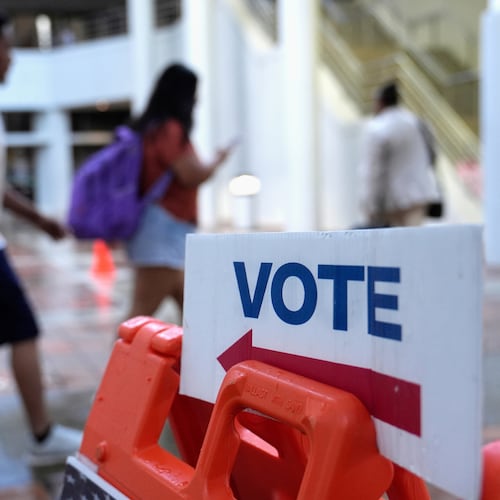 FILE - People walk past a "vote" sign on the first day of early voting in the general election in Miami, Oct. 21, 2024. (AP Photo/Lynne Sladky, File)