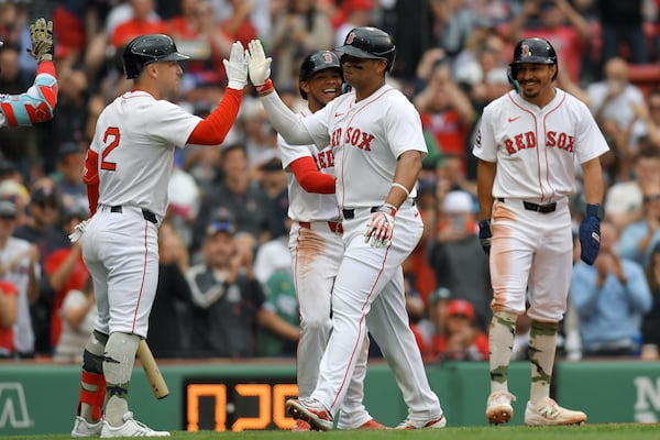 Boston Red Sox's Rafael Devers, center front, exchanges a high-five with Alex Bregman, left, as he celebrates after scoring on his grand slam in the third inning of a baseball game against the Atlanta Braves, Sunday, May 18, 2025, in Boston. (AP Photo/Steven Senne)