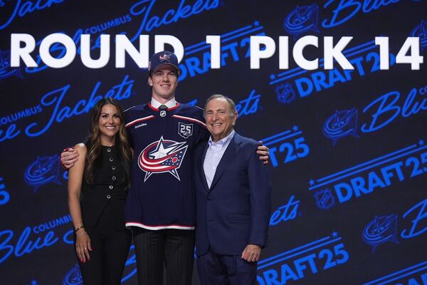 Jackson Smith, middle, stands with Meredith Gaudreau, widow of Johnny Gaudreau, left, and NHL commissioner Gary Bettman after being drafted by the Columbus Blue Jackets during the NHL hockey draft Friday, June 27, 2025, in Los Angeles. (AP Photo/Damian Dovarganes)
