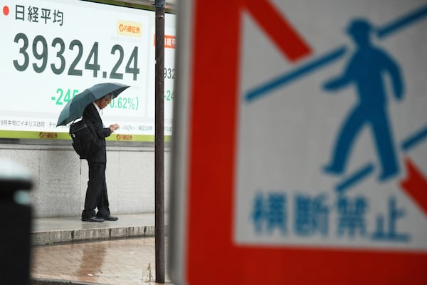 A person stands in front of an electronic stock board showing Japan's Nikkei index at a securities firm Monday, July 14, 2025, in Tokyo. (AP Photo/Eugene Hoshiko)