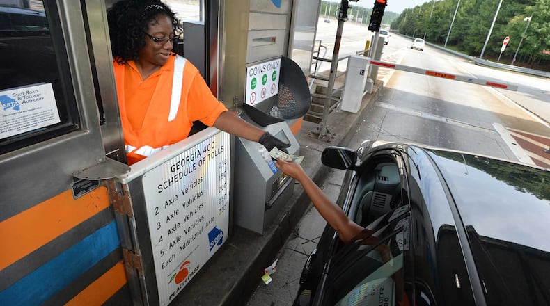 Fredricka Tyson-Holloway makes change for a customer passing through her toll booth on Ga. 400 Wednesay. Countless drivers over the years have "paid-it-forward" by donating their 50-cent change to the person waiting behind them in line at the GA 400 toll booth. But not any longer. The private company that has a contract to collect tolls for the state recently forbid toll workers from taking extra money from drivers.