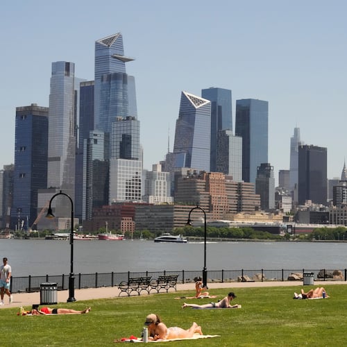 People lay out in the sun in front of the New York City skyline, in Hoboken, N.J., Wednesday, May 20, 2026. (AP Photo/Seth Wenig)