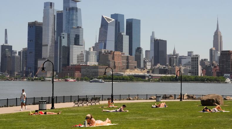 People lay out in the sun in front of the New York City skyline, in Hoboken, N.J., Wednesday, May 20, 2026. (AP Photo/Seth Wenig)