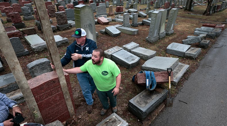 Spencer Pensoneau, center, and Ron Klump of Rosenbloom Monument Company re-set stones at Chesed Shel Emeth Cemetery in University City, mMo., on Tuesday, Feb. 21, 2017 where almost 200 gravestones were vandalized over the weekend. (Robert Cohen/St. Louis Post-Dispatch via AP)