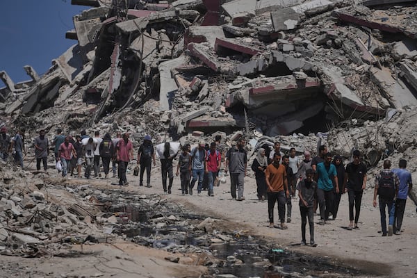 Palestinians carry sacks of humanitarian aid unloaded from trucks convoy that had been heading to Gaza City, in the northern Gaza Strip Sunday, July 20, 2025. (AP Photo/Jehad Alshrafi)