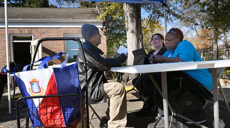The charity Intown Cares helps people navigate the safety net, including Medicaid, when they can't figure out state websites or reach someone on the phone. In this photo from November, Intown Cares Support Specialist Tanya Davenport, in blue, speaks with a client, Jose Roldan, as intern Chelsea Piccirilli listens. They hold their periodic support sessions behind Druid Hills Presbyterian Church where the Intown Food Pantry operates. On the day this photo was taken several clients were trying to figure out their status in Medicaid redetermination and how to stay enrolled. (PHOTO by Hyosub Shin / Hyosub.Shin@ajc.com)