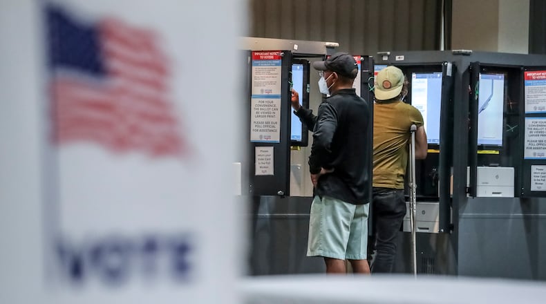 Voters Michael Parks and Brett Ringel cast ballots on Tuesday, Nov. 8, 2022 at Antioch Baptist Church in Atlanta. (John Spink / John.Spink@ajc.com)